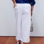 Person wearing a blue shirt and white pants with a neutral background