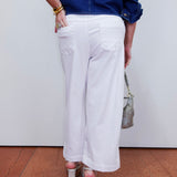 Person wearing a blue shirt and white pants with a neutral background