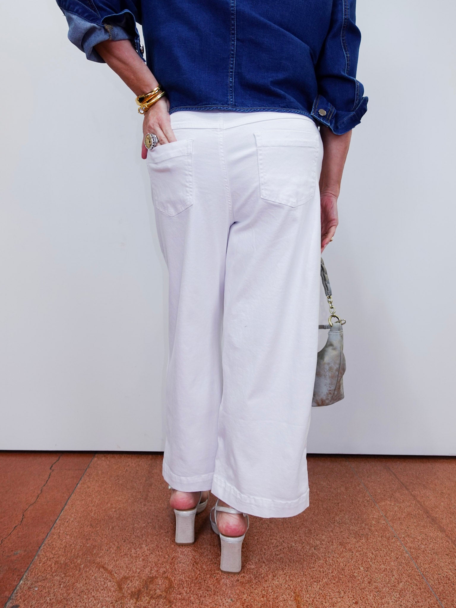 Person wearing a blue shirt and white pants with a neutral background