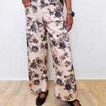Person wearing floral pants and black shoes on a plain background