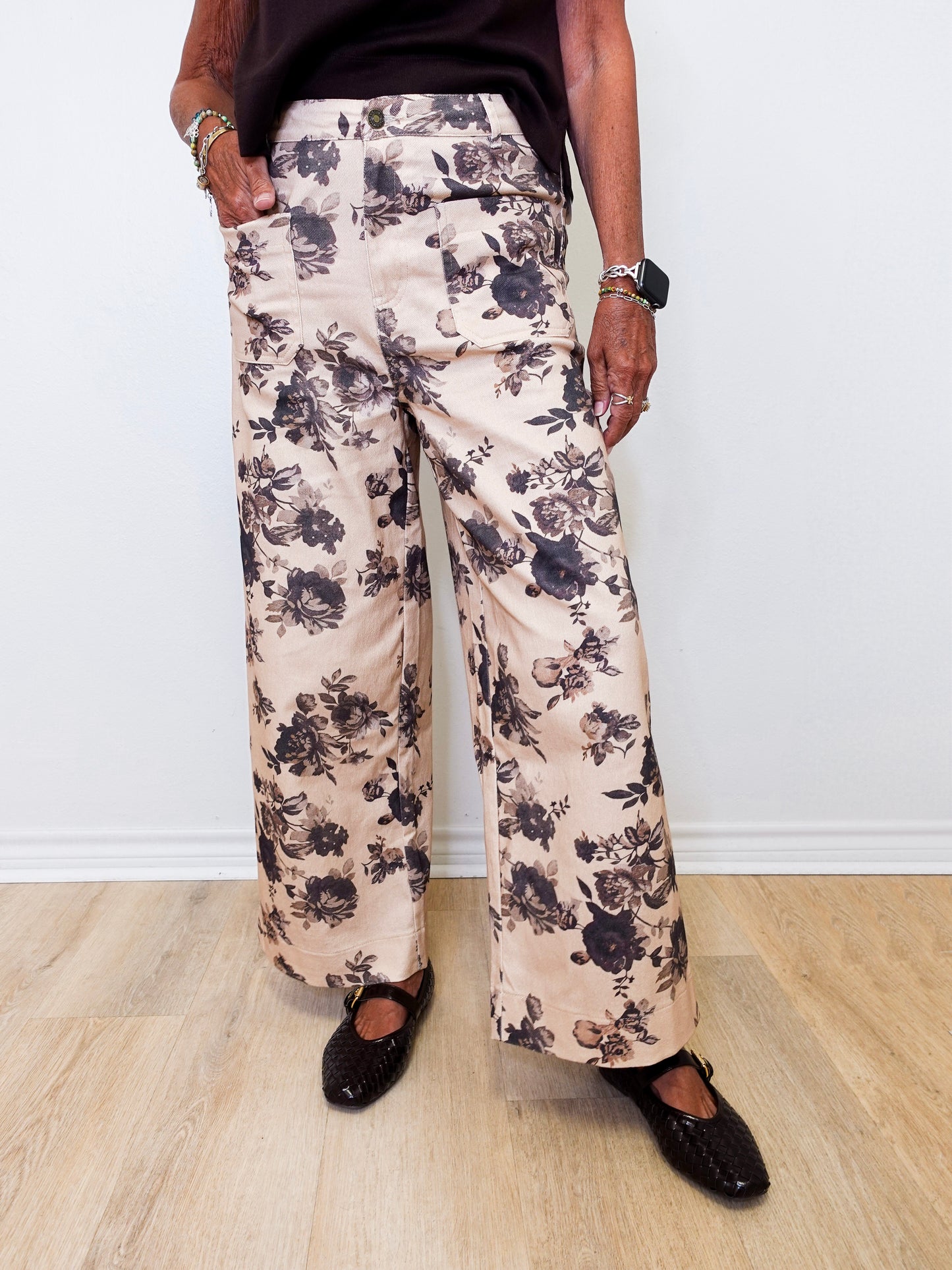 Person wearing floral pants and black shoes on a plain background