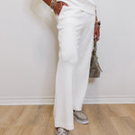 Person wearing a white outfit with white shoes on a wooden floor.