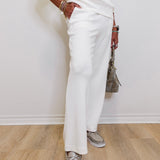 Person wearing a white outfit with white shoes on a wooden floor.