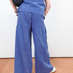 Person wearing blue pants and a matching top against a white wall.