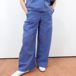 Person wearing blue scrubs with white shoes on a plain background