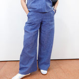 Person wearing blue scrubs with white shoes on a plain background