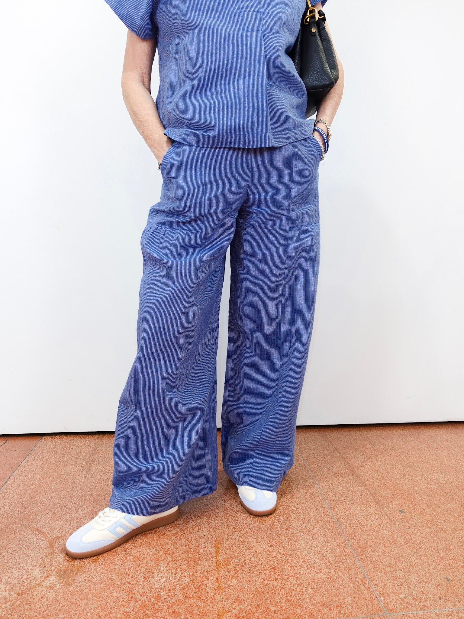 Person wearing blue scrubs with white shoes on a plain background