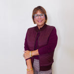 Woman wearing a purple jacket and glasses against a white background