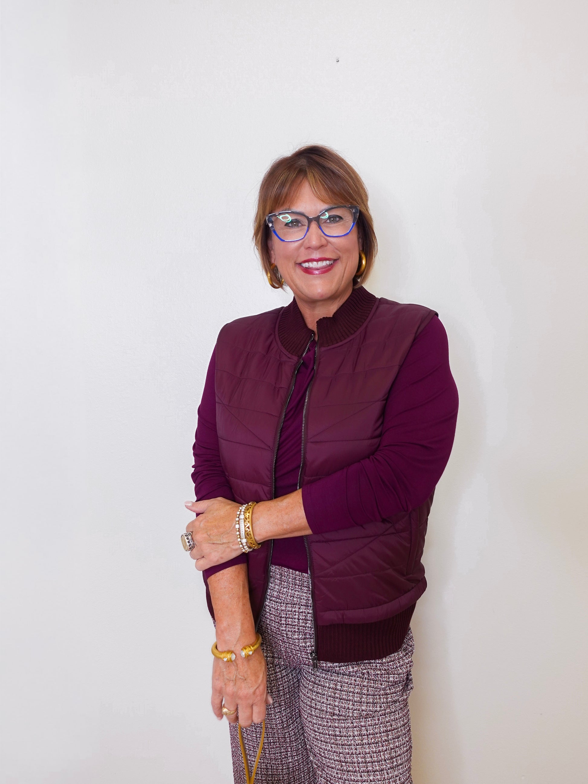 Woman wearing a purple jacket and glasses against a white background
