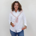 Woman wearing a white blouse with a striped tie and blue jeans against a plain background