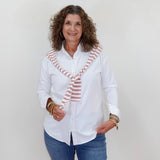 Woman wearing a white blouse with a striped tie and blue jeans against a plain background