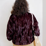 Person wearing a dark brown faux fur jacket against a white background