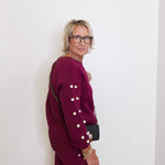 Person wearing a burgundy outfit with white buttons against a white background