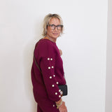 Person wearing a burgundy outfit with white buttons against a white background