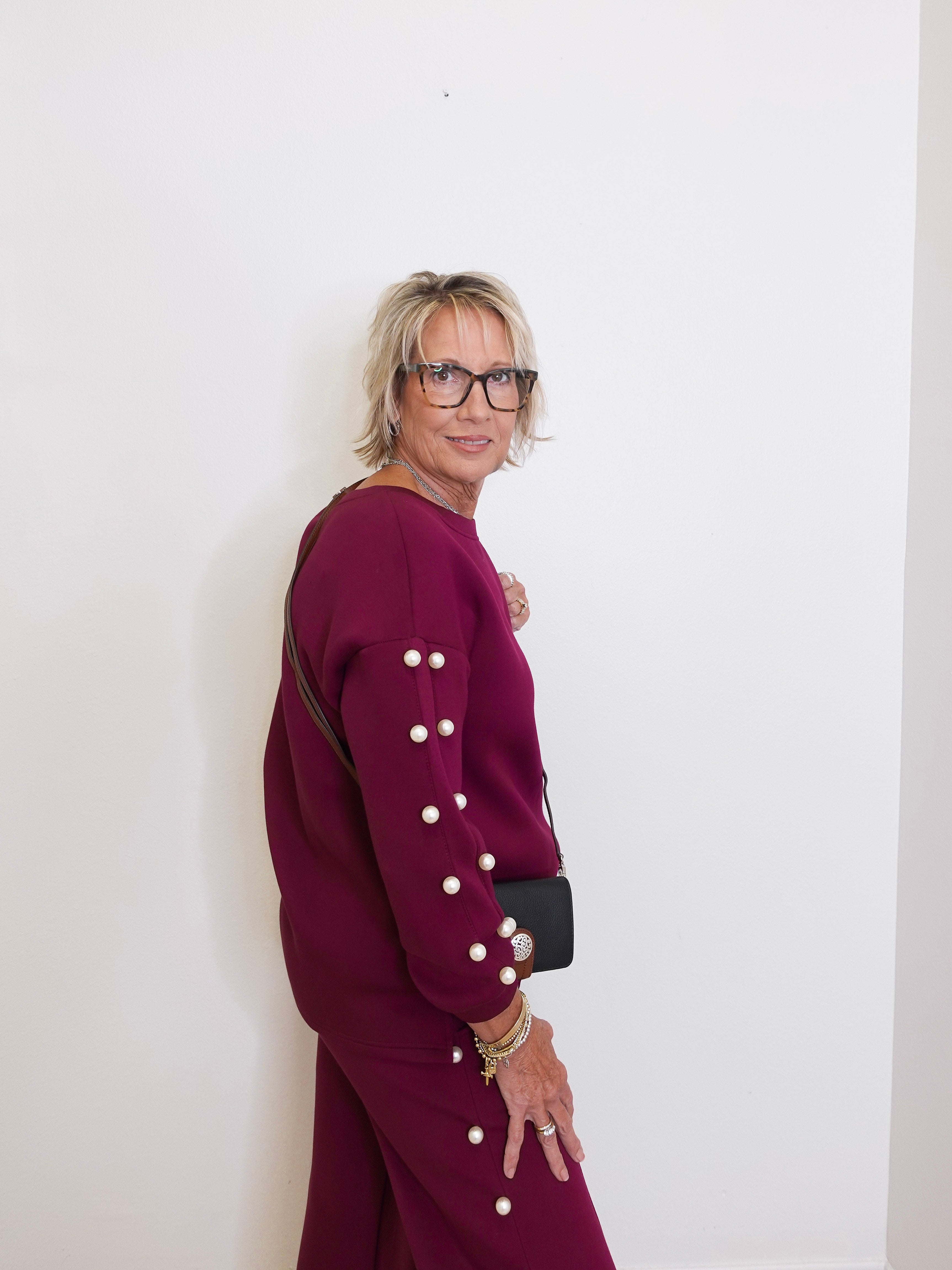 Person wearing a burgundy outfit with white buttons against a white background
