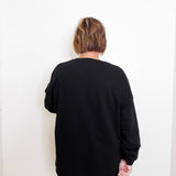 Person wearing a black sweater against a white background