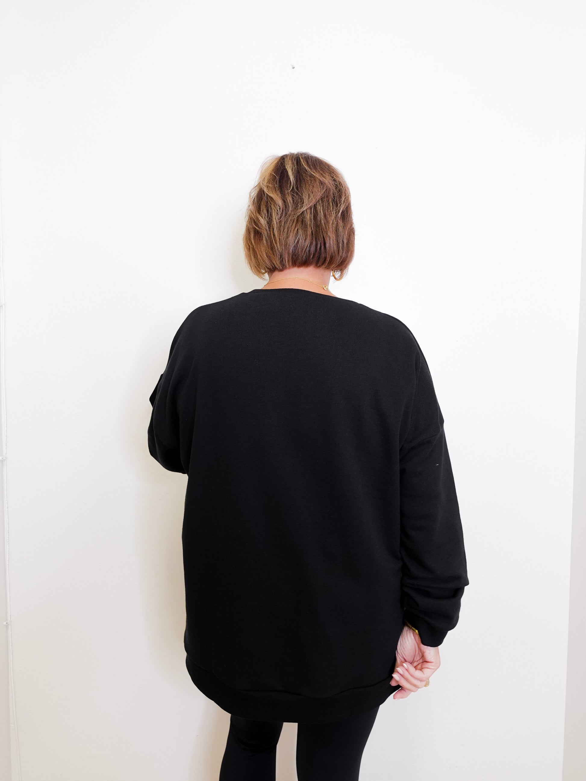Person wearing a black sweater against a white background