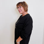 Woman wearing a black outfit with glasses against a white background
