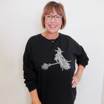 Woman wearing a black sweatshirt with a witch design on a white background
