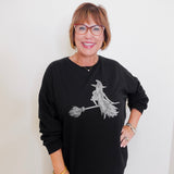 Woman wearing a black sweatshirt with a witch design on a white background