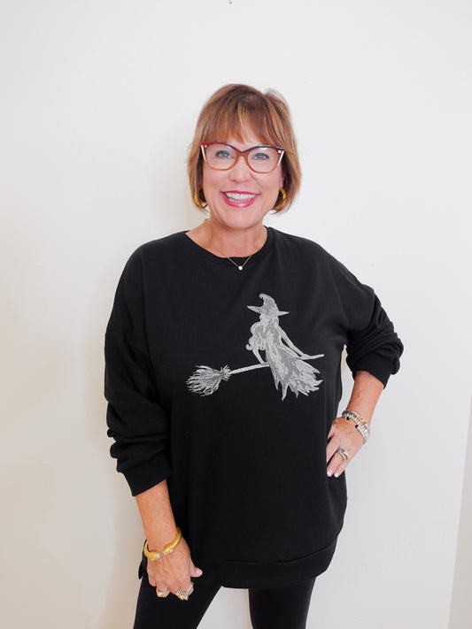Woman wearing a black sweatshirt with a witch design on a white background