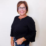 Woman wearing a black top and blue jeans with a white background