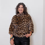 Woman wearing a leopard print sweater against a white wall