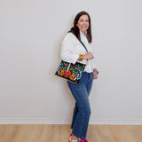 Woman holding a colorful handbag against a white wall