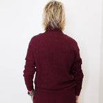 Person wearing a maroon sweater and pants against a white background