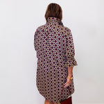 Person wearing a patterned dress against a white wall