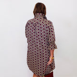 Person wearing a patterned dress against a white wall