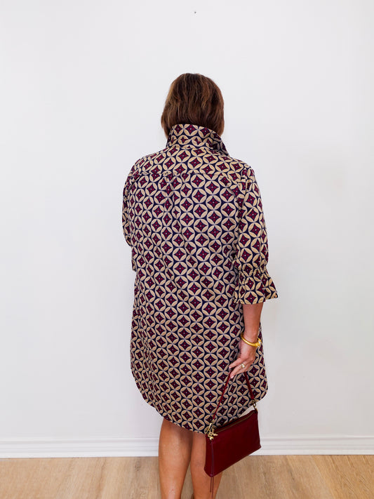 Person wearing a patterned dress against a white wall