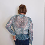 Person wearing a patterned blouse with a plain background