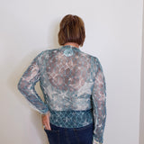 Person wearing a patterned blouse with a plain background
