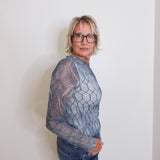 Person wearing a textured gray sweater and blue jeans against a plain background