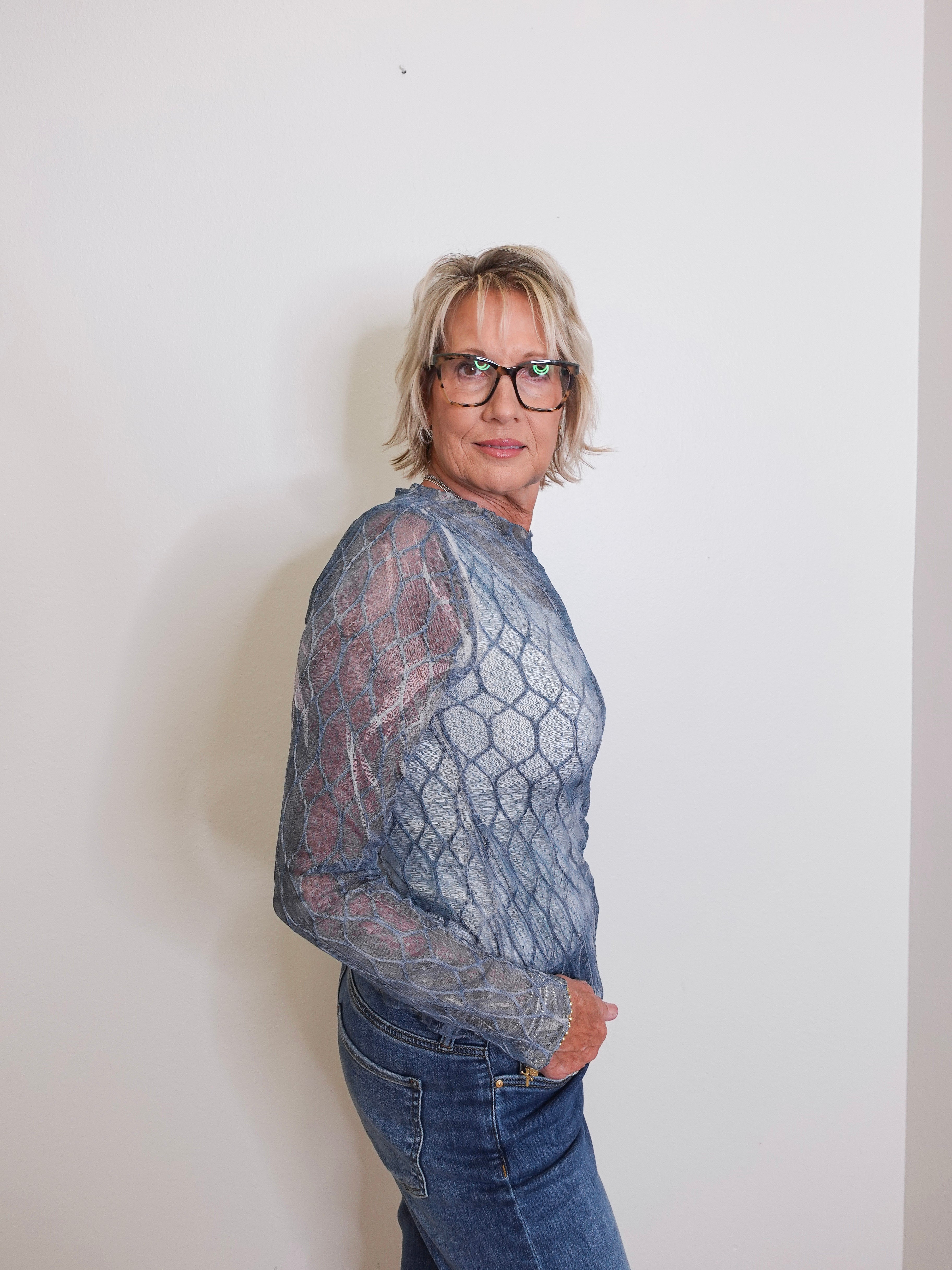 Person wearing a textured gray sweater and blue jeans against a plain background
