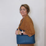 Woman holding a blue handbag against a white wall