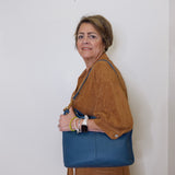 Woman holding a blue handbag against a white wall