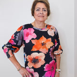 Woman wearing a floral blouse against a plain background