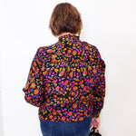 Person wearing a colorful floral shirt against a white background