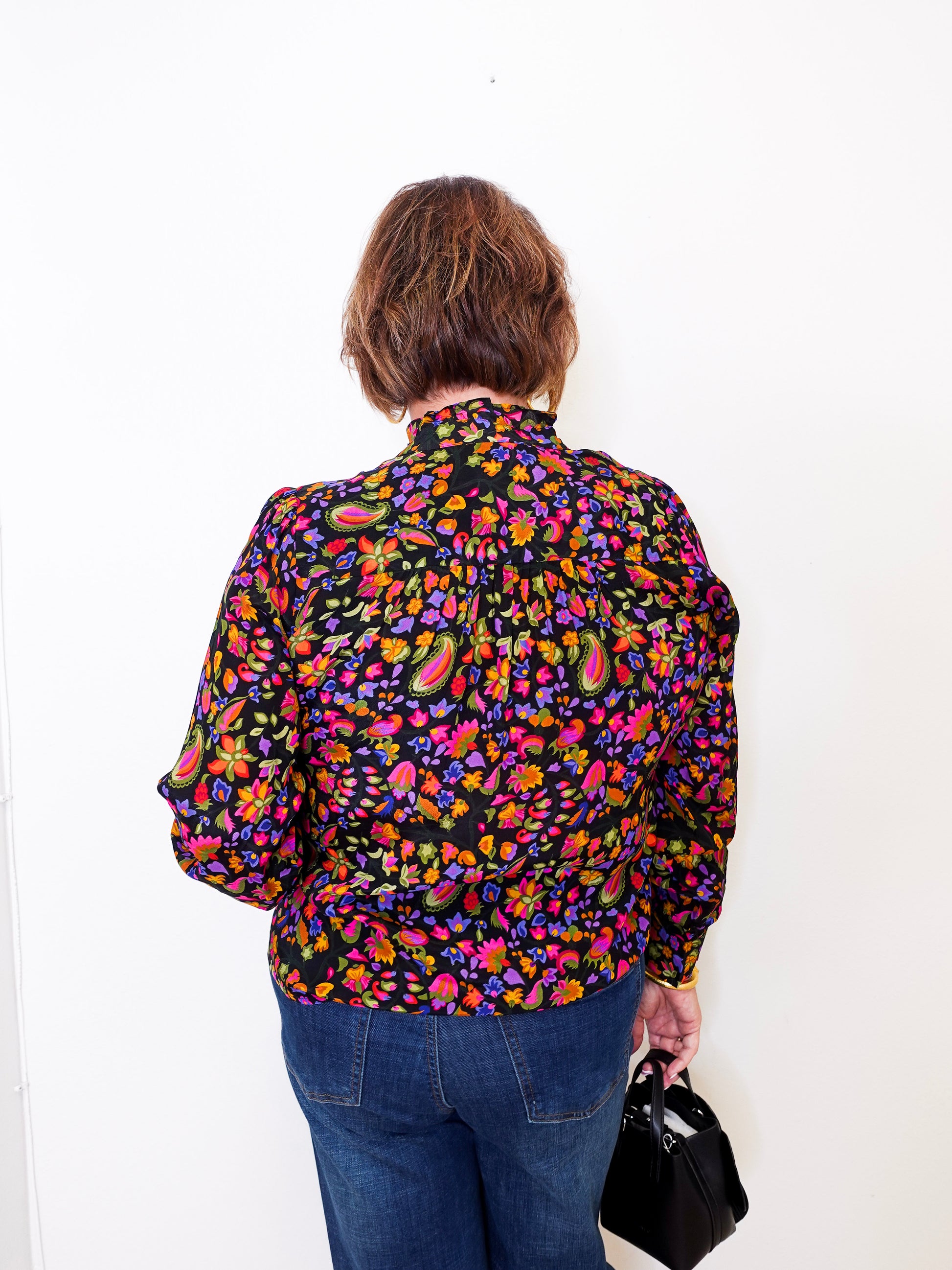 Person wearing a colorful floral shirt against a white background