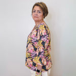 Woman wearing a floral blouse against a white wall