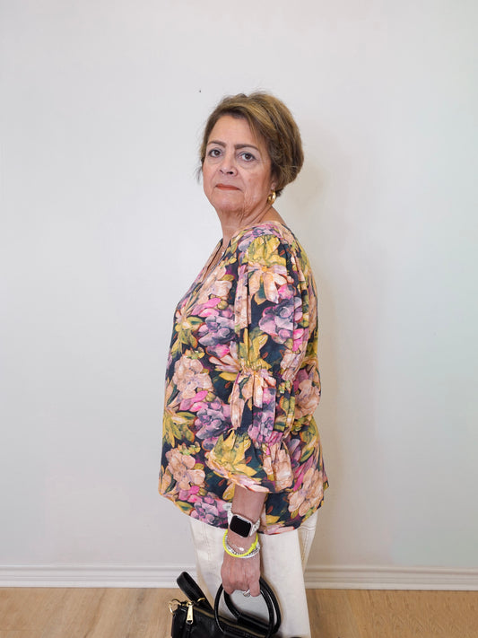 Woman wearing a floral blouse against a white wall