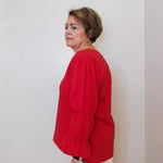 Person wearing a red shirt against a white wall