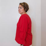 Person wearing a red shirt against a white wall