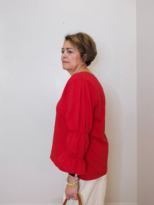 Person wearing a red shirt against a white wall
