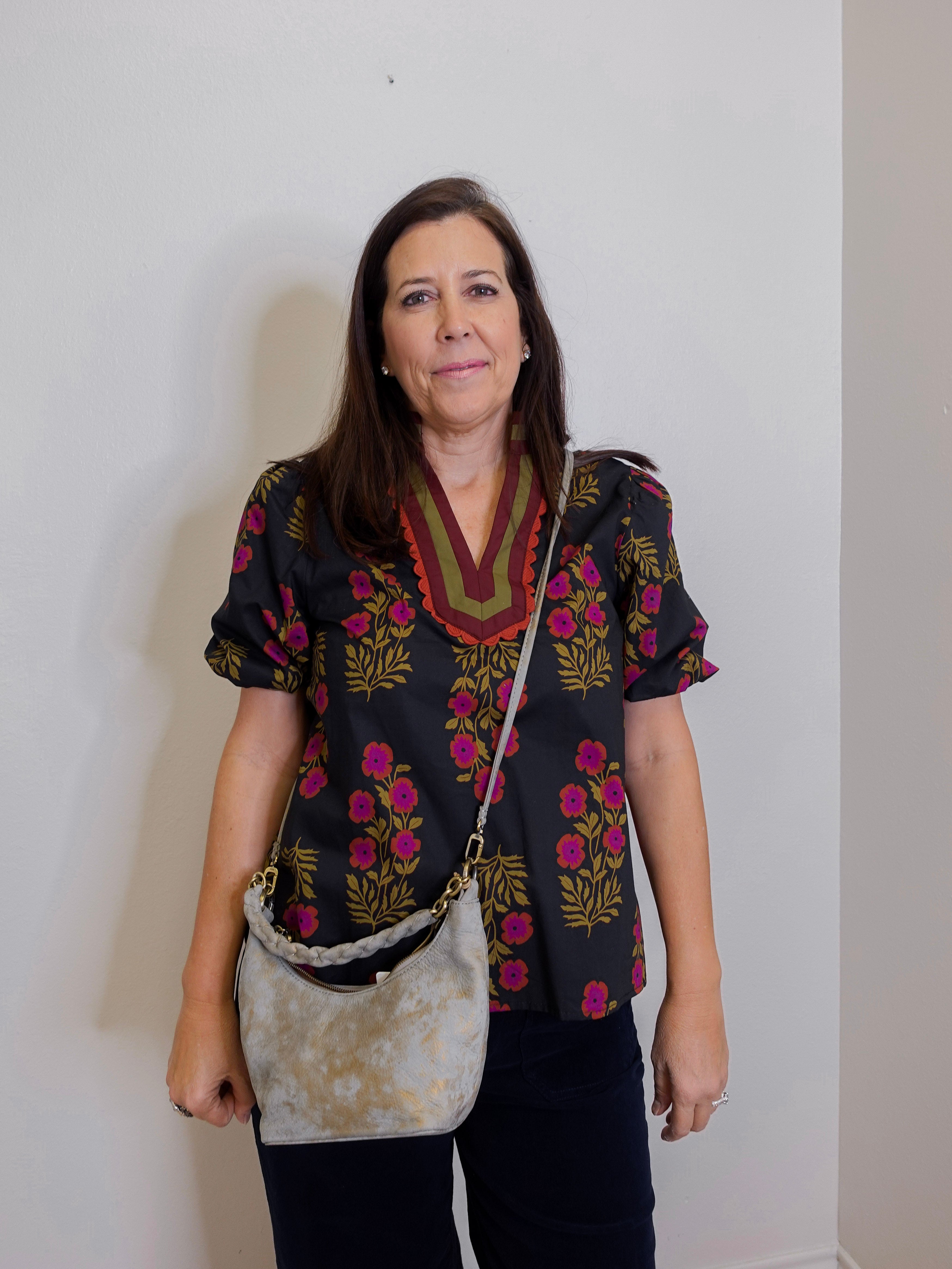 woman wearing a gray suede handbag with braided handle on a white background