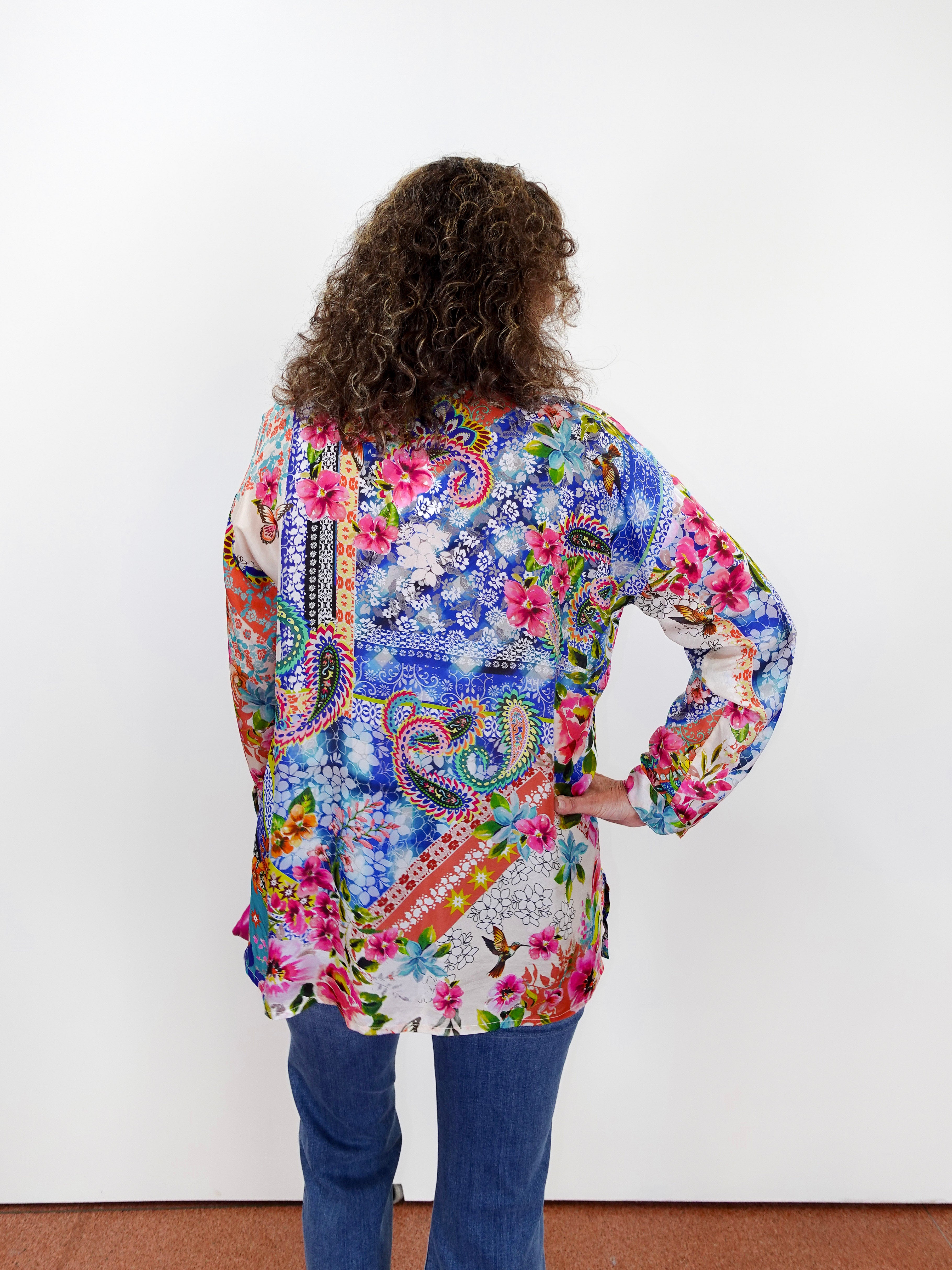 Person wearing a colorful patterned shirt with their back to the camera on a white background