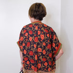 a women wearing a black floral short sleeve top in front of a white background 