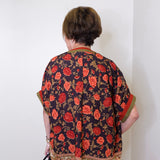a women wearing a black floral short sleeve top in front of a white background 